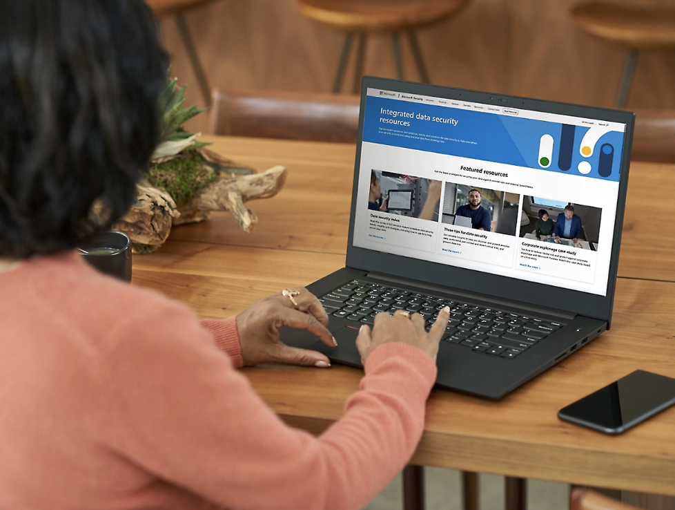 Person using a laptop at a wooden table, viewing Microsoft's data security and governance page—highlighting Microsoft Purview’s Azure-native capabilities.